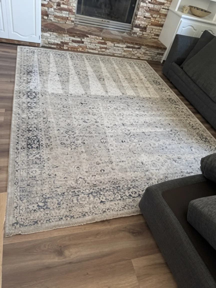 Large ivory patterned area rug freshly cleaned on hardwood in front of a brick fireplace